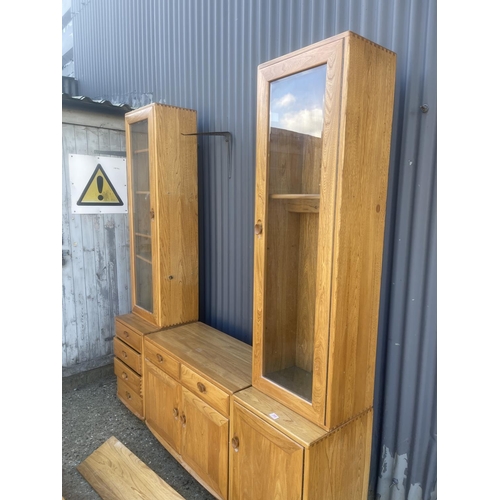 399 - An ercol light elm dresser with three section base with two glazed cabinet tops with two floating sh... 