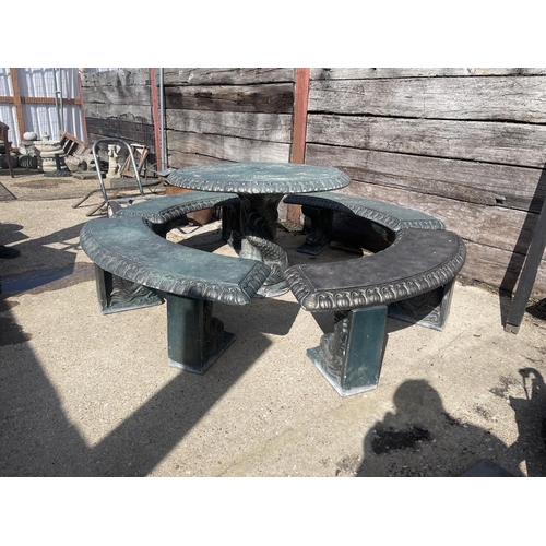 490 - A large green painted concrete circular garden table together with a set of four curved garden bench... 