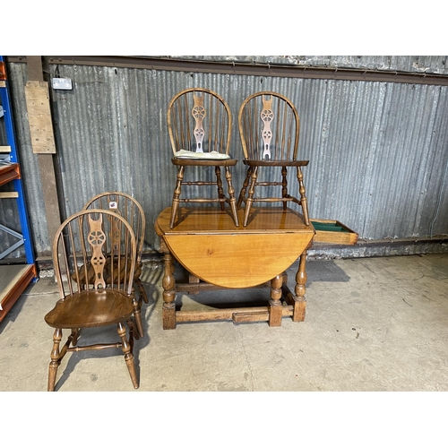 58 - An oak gateleg dining table with long drawer together with four wheelback dining chairs