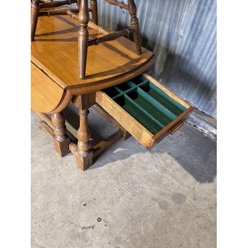 58 - An oak gateleg dining table with long drawer together with four wheelback dining chairs