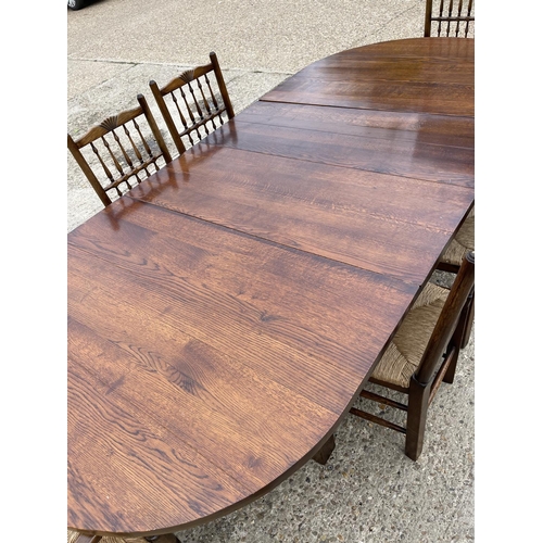 80 - A large reproduction oak dining table with two extension leaves marked GMC to base, together with si... 