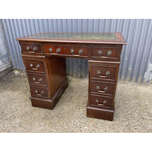 83 - A small mahogany pedestal desk with a green leather top