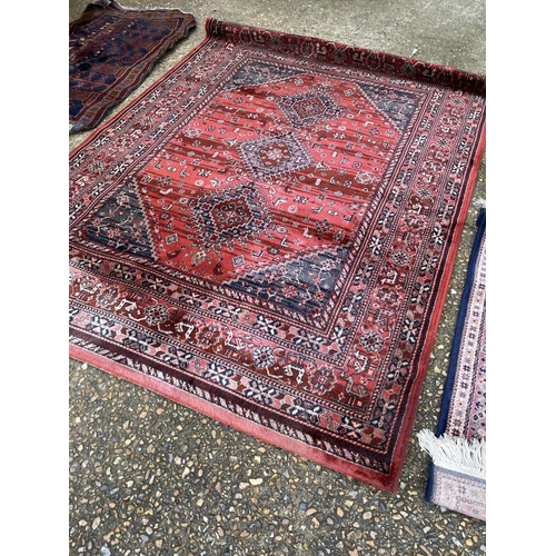 105 - A large modern red pattern rug together with two other oriental rugs