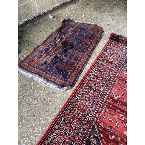 105 - A large modern red pattern rug together with two other oriental rugs