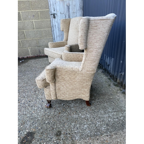 128 - A pair of cream upholstered wing back armchairs