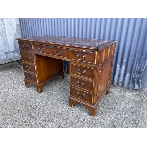 167 - A reproduction yew pedestal desk with a brown leather top