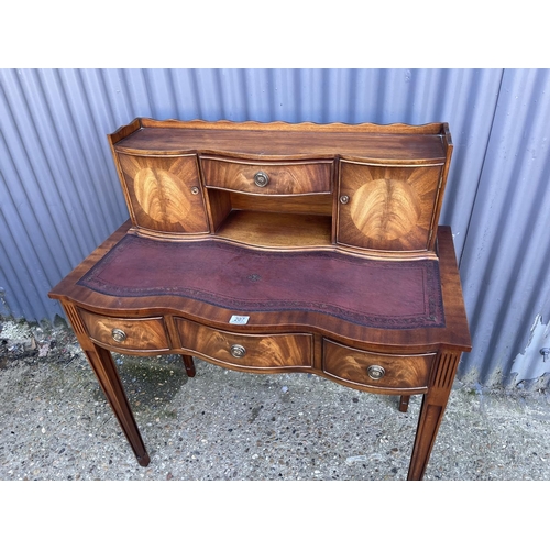 207 - A reproduction mahogany ladies writing table with a brown leather top