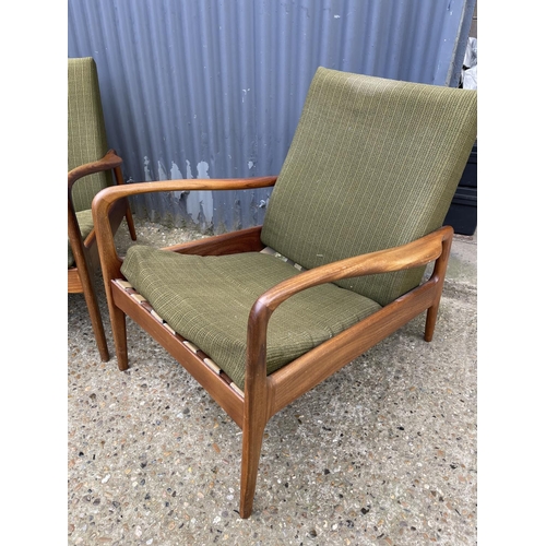 170 - A pair of mid century teak framed lounge chairs labelled GREAVES AND THOMAS with green upholstery