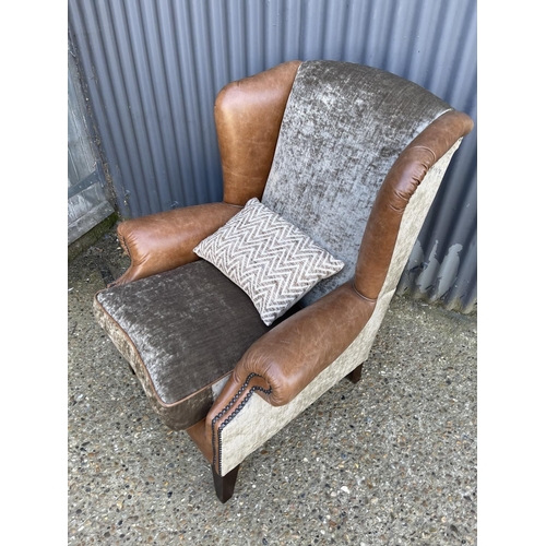 177 - A tan brown leather wing back armchair with crush velvet seat by TETRAD