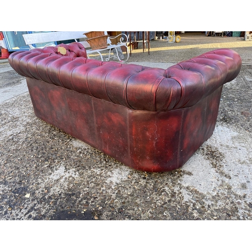 257 - An oxblood red leather chesterfield sofa for reupholstery