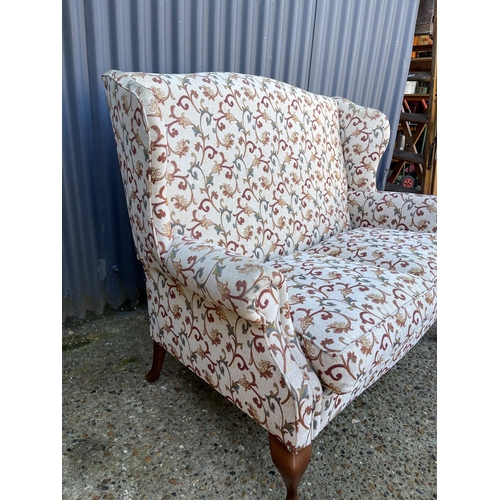 39 - A white and red pattern wing back two seater sofa