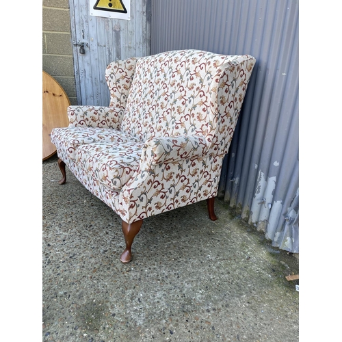 39 - A white and red pattern wing back two seater sofa