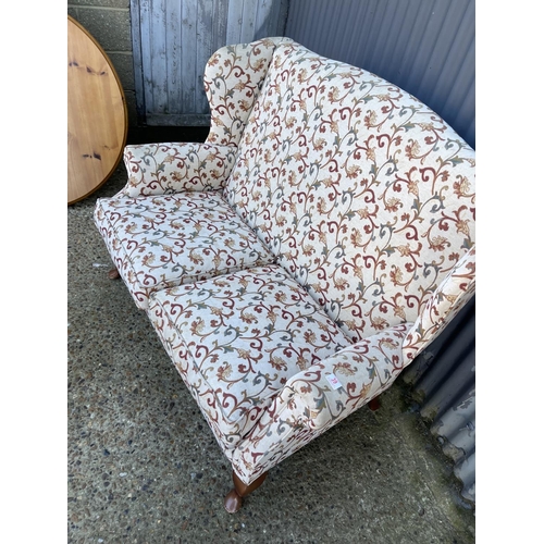 39 - A white and red pattern wing back two seater sofa