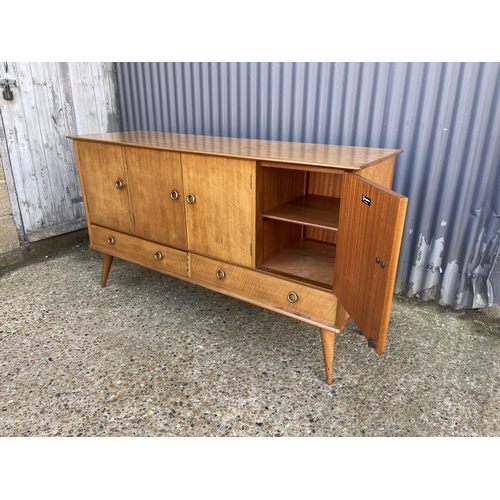 66 - A mid century four door and two drawer sideboard in French walnut by YOUNGER retailed and labelled H... 