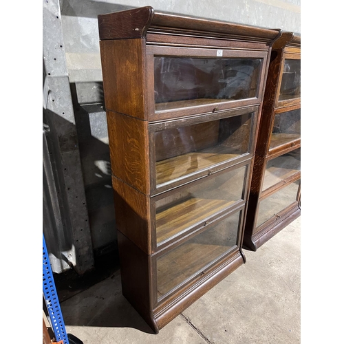 141 - An early 20th century four section oak bookcase with glazed up and over doors by GUNN