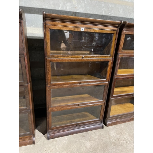 142 - An early 20th century four section oak bookcase with glazed up and over doors by GUNN