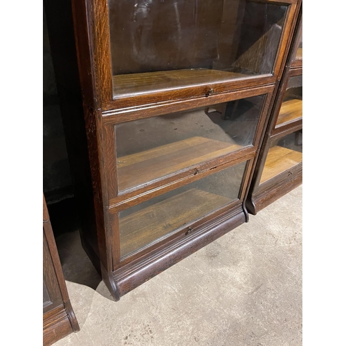 142 - An early 20th century four section oak bookcase with glazed up and over doors by GUNN