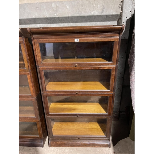 143 - An early 20th century four section oak bookcase with glazed up and over doors by GUNN