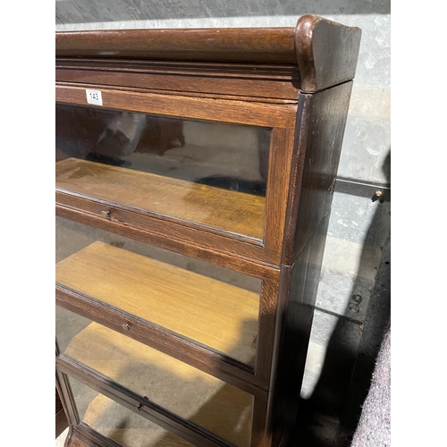 143 - An early 20th century four section oak bookcase with glazed up and over doors by GUNN