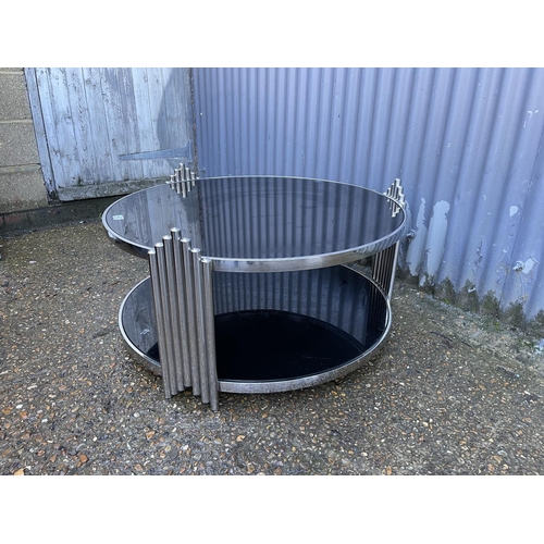 147 - A modern style circular chrome framed coffee table with black glass tops