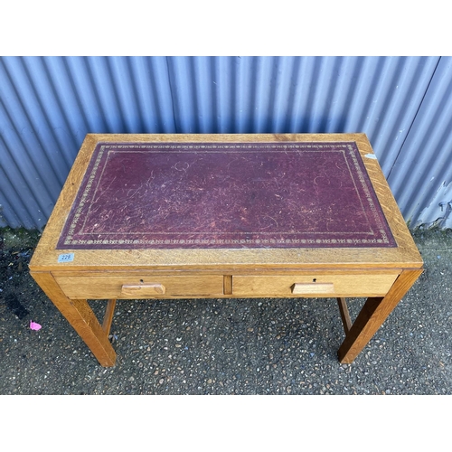 228 - A mid century oak two drawer office desk with a red leather top