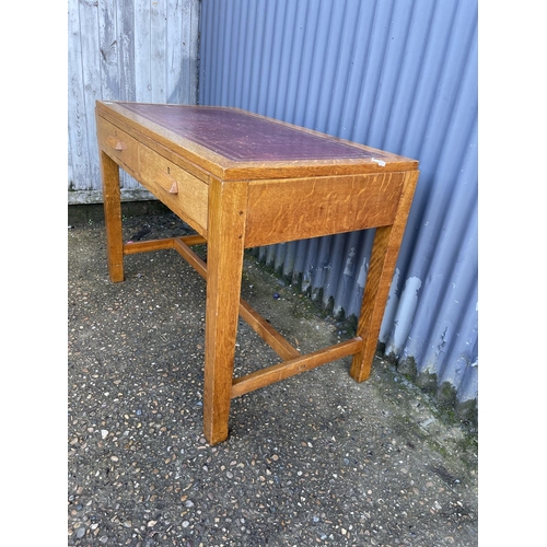 228 - A mid century oak two drawer office desk with a red leather top