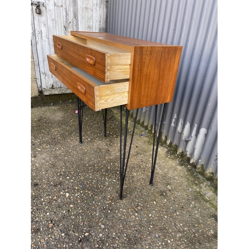 232 - A teak hall table / chest of two drawers raised on hairpin legs