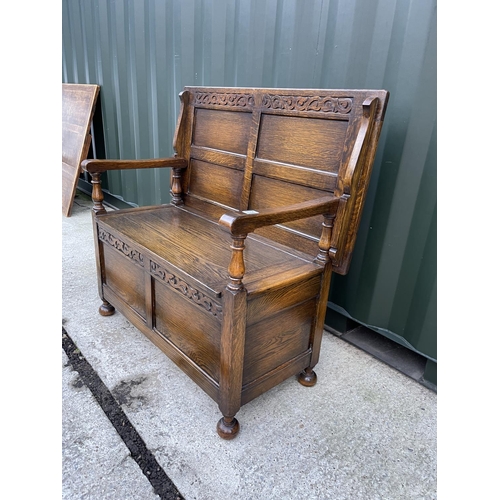 273 - A large early 20th century oak monks bench carved to the front