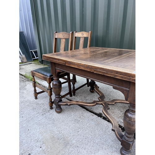 274 - An early 20th century oak drawer leaf table and four oak chairs