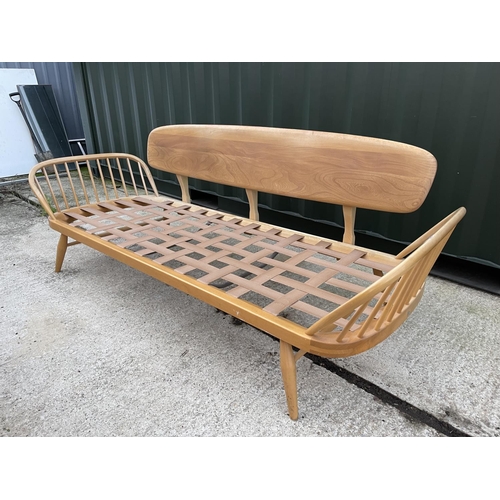 281 - An original ercol light elm day bed with web seat, removable plank back board and original cushion s... 