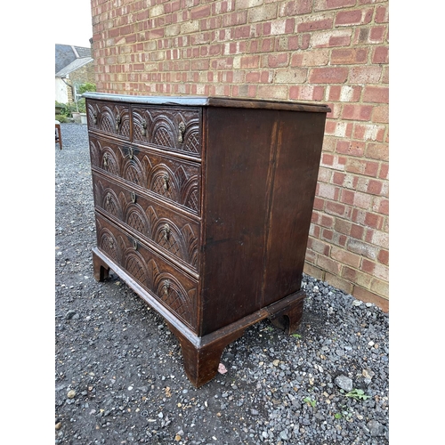 337 - An antique oak chest of five drawers carved to the front and fitted with brass drop handles