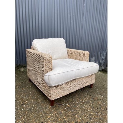 34 - A modern rattan style armchair with linen upholstered cushions