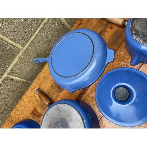 371 - A chrome pan stand loaded with a graduated set of LE CREUSET pans together with two frying pans