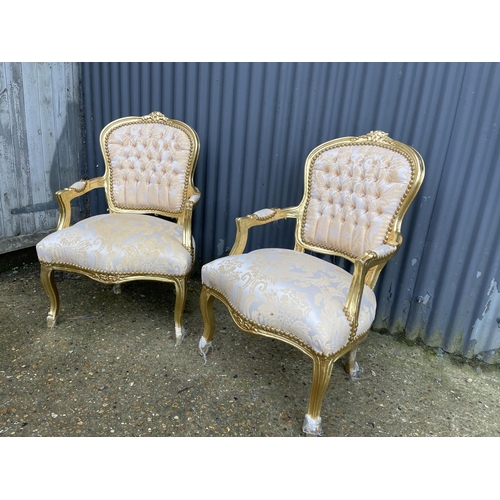 64 - A pair of gold gilt and gold pattern upholstered throne style armchairs