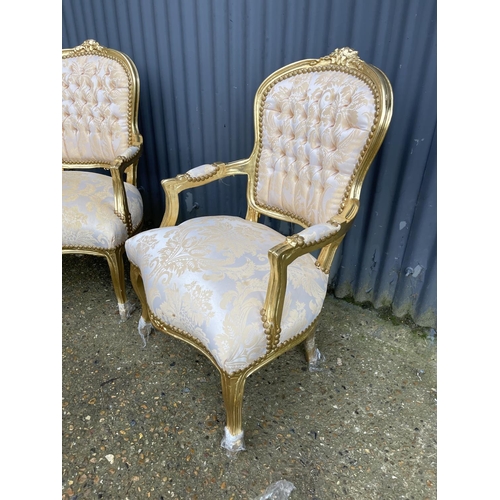 64 - A pair of gold gilt and gold pattern upholstered throne style armchairs