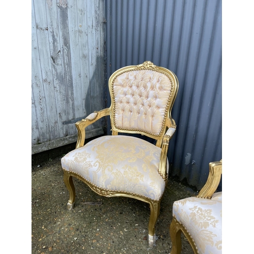 64 - A pair of gold gilt and gold pattern upholstered throne style armchairs