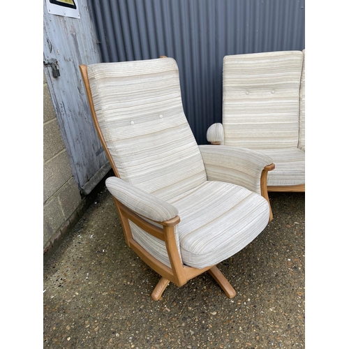 69 - A MODERN ERCOL upholstered two seater recliner sofa together with matching revolving armchair with s... 