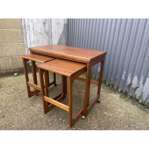 121 - A mid century teak trolley nest of three tables with fold over top