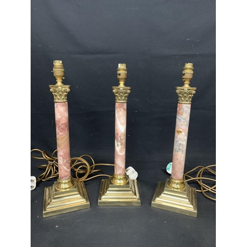 685 - Set of three pink marble and brass column table lamps, height 46 cms