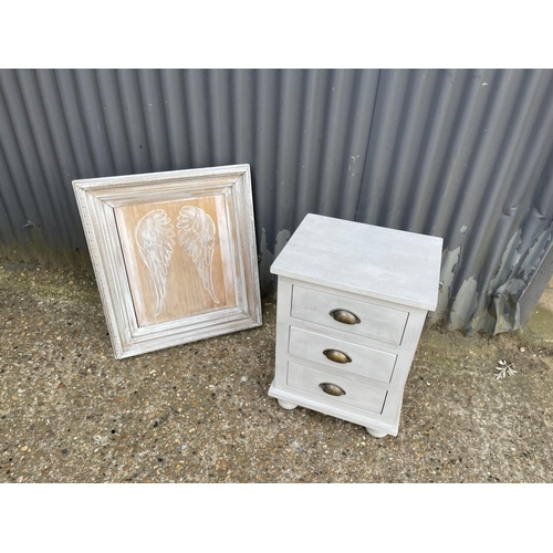 199 - A grey painted bedside chest of three together with painted angel wings in frame