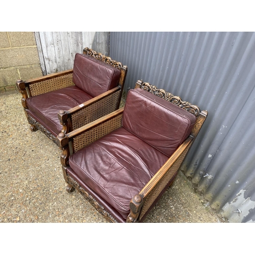 31 - A pair of early 20th century carved oak framed begere armchairs, upholstered in maroon leather