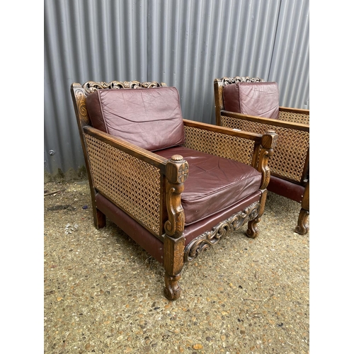 31 - A pair of early 20th century carved oak framed begere armchairs, upholstered in maroon leather