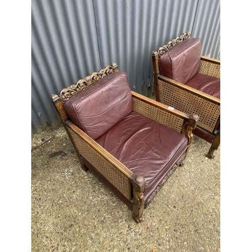 31 - A pair of early 20th century carved oak framed begere armchairs, upholstered in maroon leather