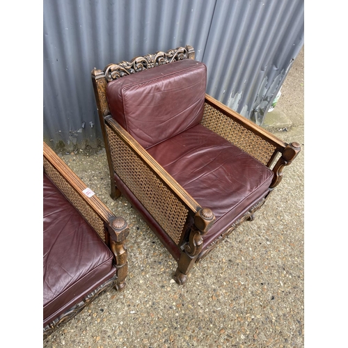 31 - A pair of early 20th century carved oak framed begere armchairs, upholstered in maroon leather