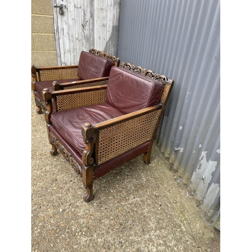 31 - A pair of early 20th century carved oak framed begere armchairs, upholstered in maroon leather