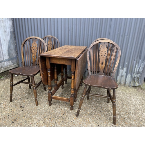 43 - An oak gateleg table together with a set of four wheel back dining chairs