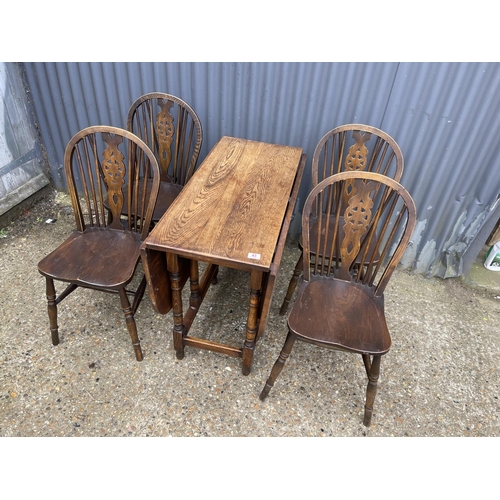 43 - An oak gateleg table together with a set of four wheel back dining chairs