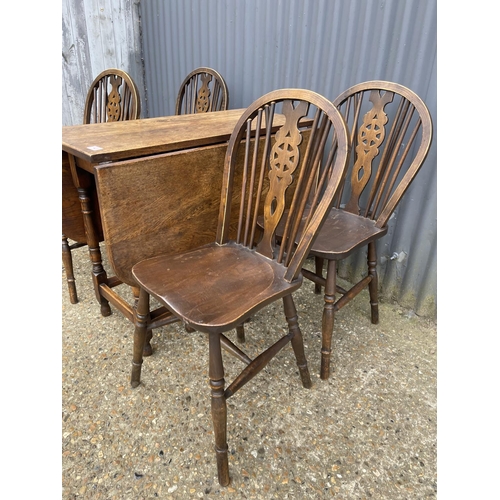 43 - An oak gateleg table together with a set of four wheel back dining chairs