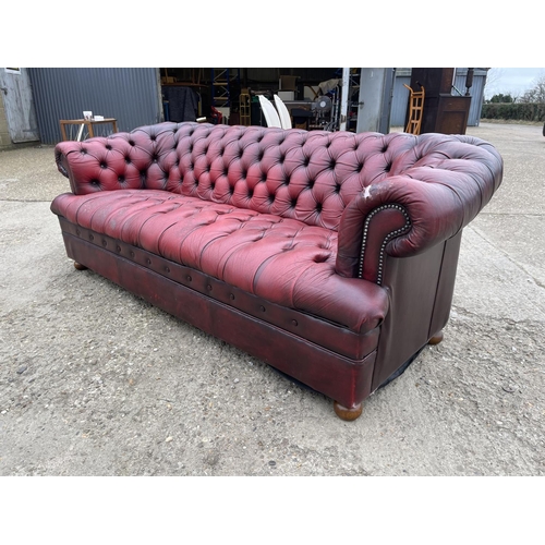 111 - A red leather chesterfield three seater sofa with deep buttoned seat.