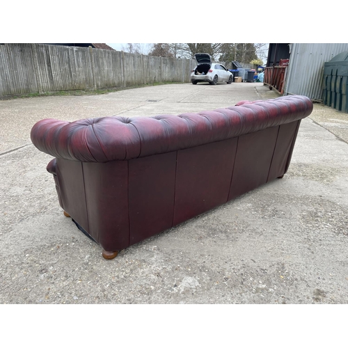 111 - A red leather chesterfield three seater sofa with deep buttoned seat.